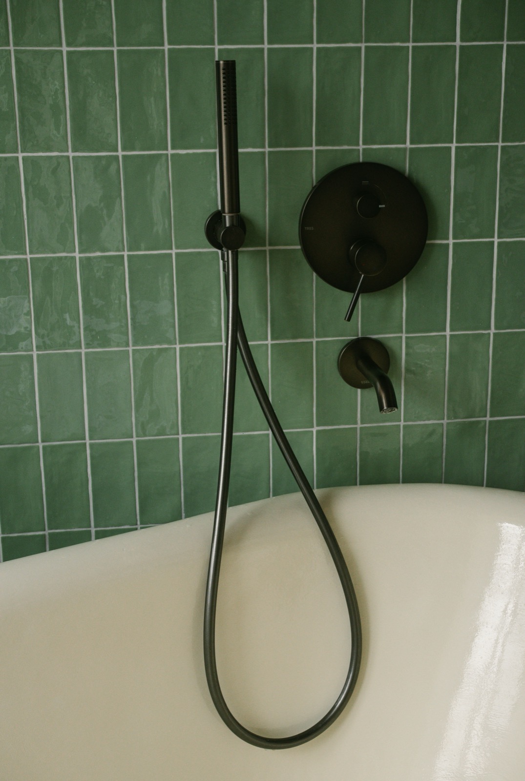 Grüne handwerklich wirkende Fliesen an einer Badewanne